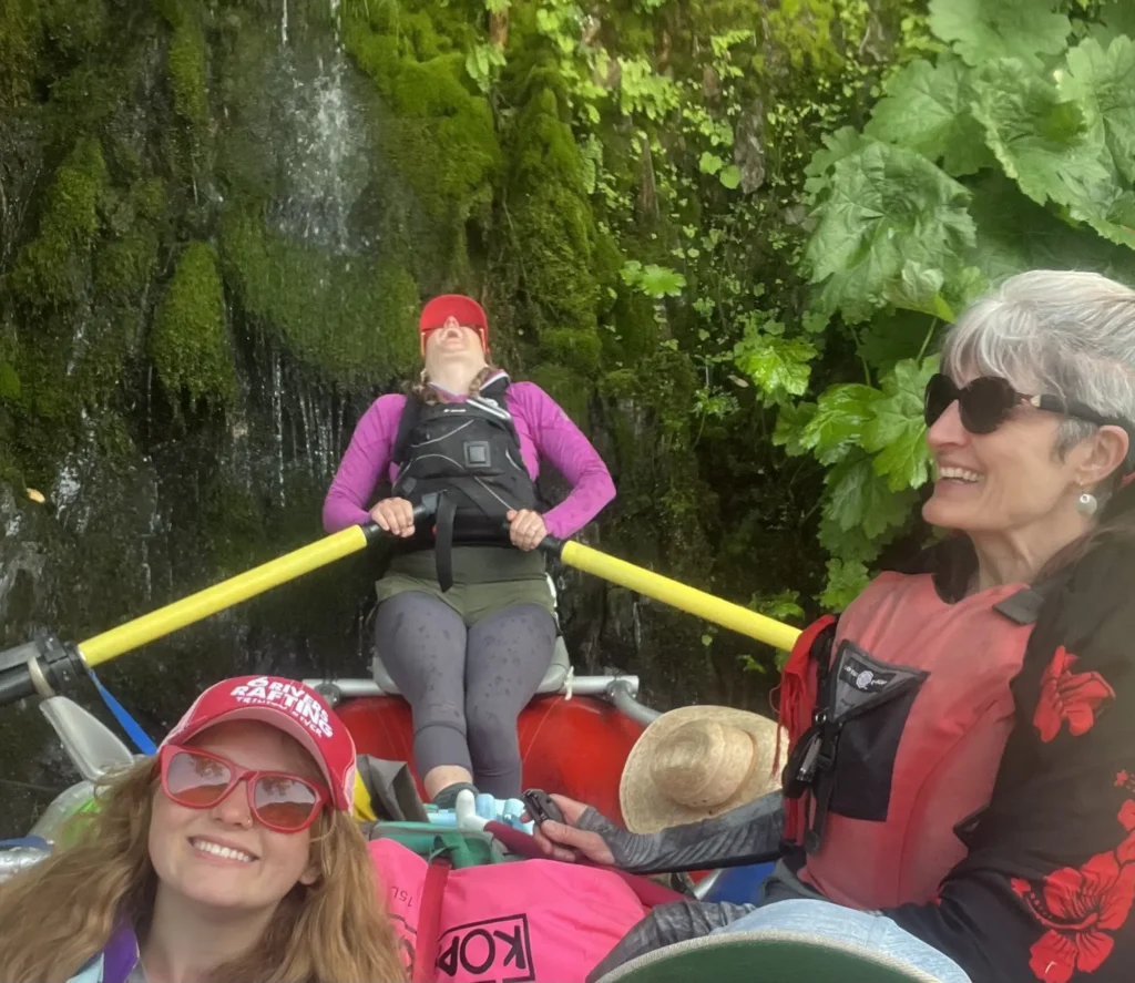 Three women in a raft, two are smiling one is laughing